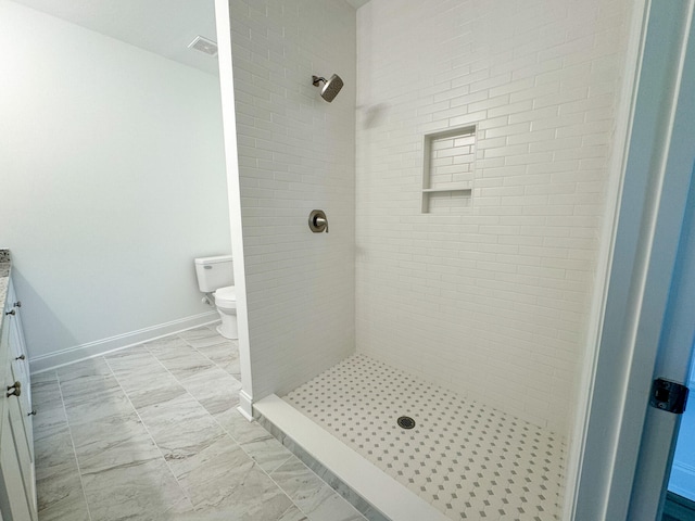 bathroom featuring toilet, a tile shower, vanity, and tile patterned floors