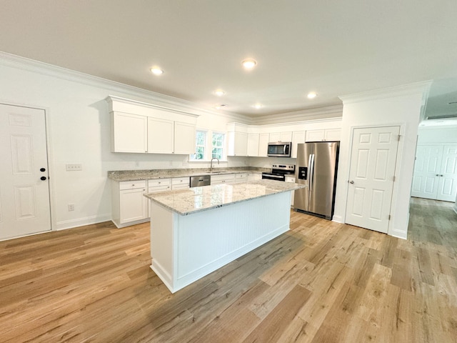 kitchen with light hardwood / wood-style flooring, a kitchen island, white cabinetry, crown molding, and stainless steel appliances