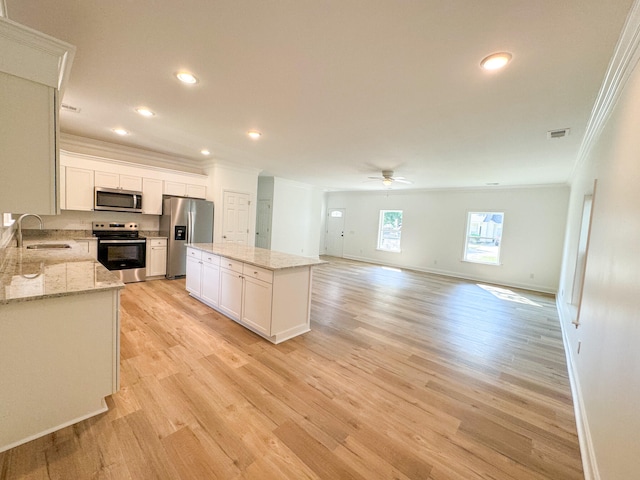 kitchen featuring sink, light wood-type flooring, a kitchen island, and stainless steel appliances