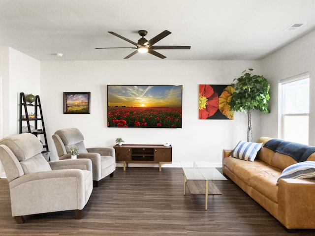 living area with baseboards, visible vents, a ceiling fan, and dark wood-type flooring