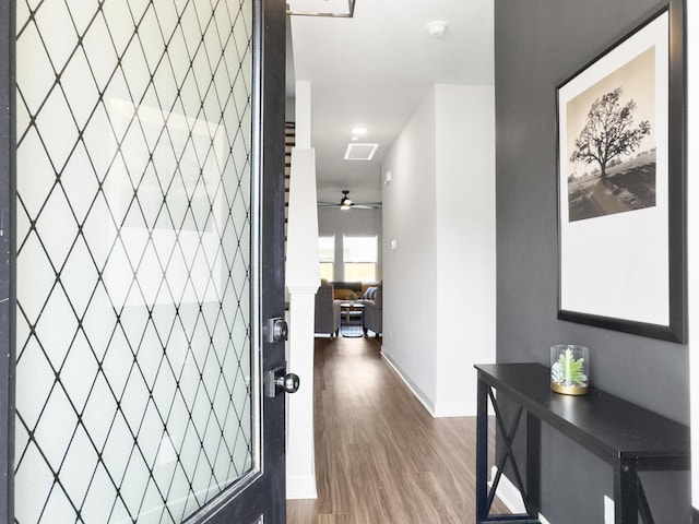 hallway with baseboards, visible vents, and wood finished floors