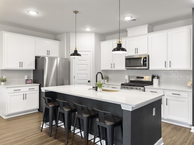 kitchen featuring a sink, a kitchen breakfast bar, stainless steel appliances, tasteful backsplash, and visible vents