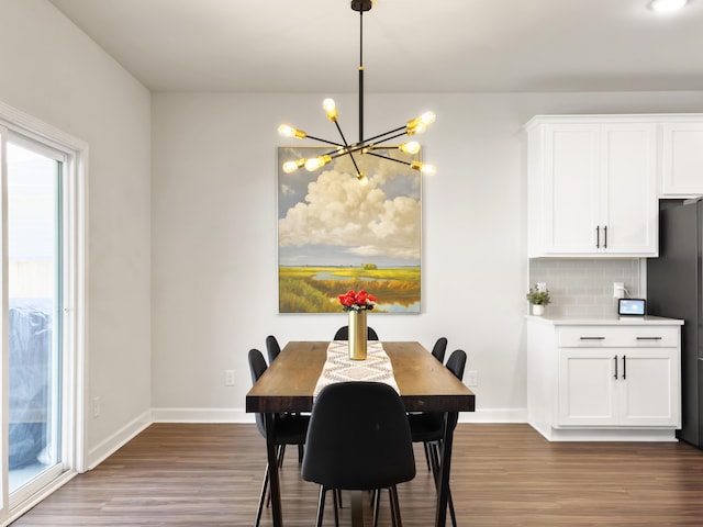 dining space featuring baseboards, an inviting chandelier, and wood finished floors