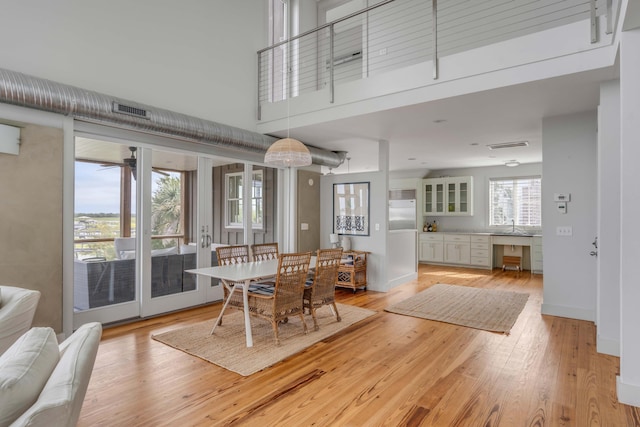 dining space with light wood-type flooring and a high ceiling