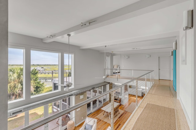 corridor featuring beam ceiling and a wealth of natural light