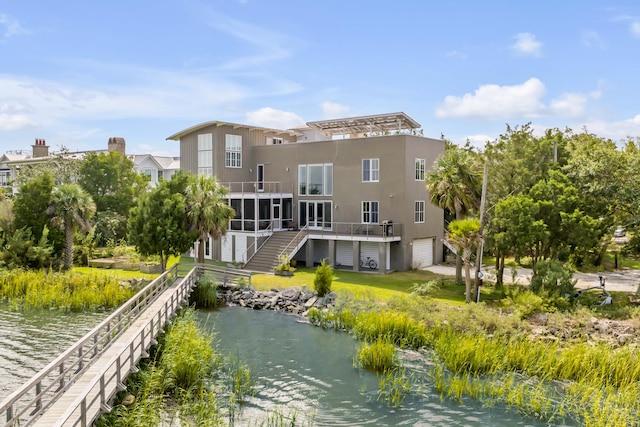 rear view of property featuring a deck with water view and a sunroom