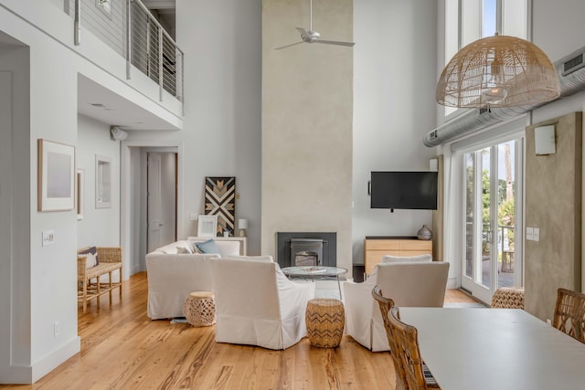 living room with a towering ceiling, light hardwood / wood-style flooring, and ceiling fan