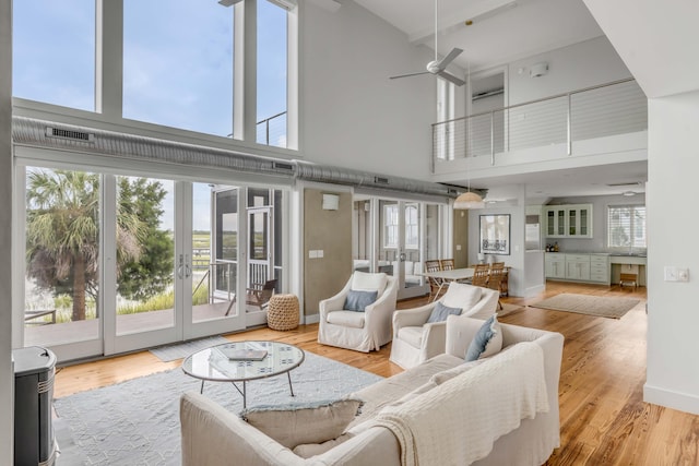 living room featuring light wood-type flooring, french doors, and a towering ceiling