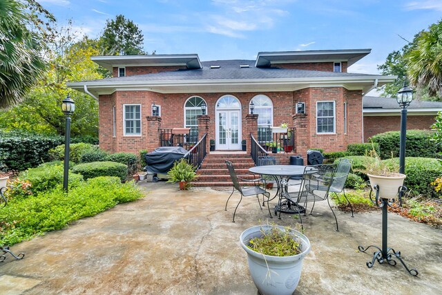 rear view of house featuring french doors, outdoor dining space, brick siding, and a patio area