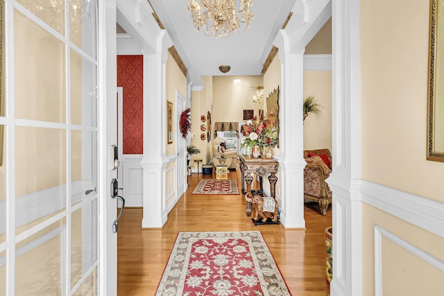 entrance foyer featuring light wood-type flooring, crown molding, and ornate columns