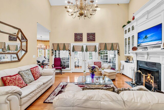 living room featuring light wood-type flooring, a chandelier, and a high ceiling