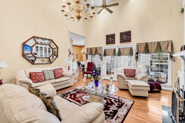 living room featuring a high ceiling, ceiling fan with notable chandelier, and wood finished floors