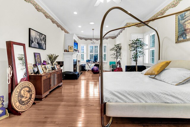bedroom featuring recessed lighting, ornamental molding, a fireplace with raised hearth, and wood finished floors