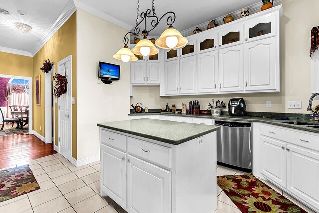 kitchen with light tile patterned floors, dark countertops, crown molding, and stainless steel dishwasher