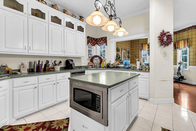 kitchen with white cabinets, light hardwood / wood-style flooring, stainless steel microwave, and pendant lighting