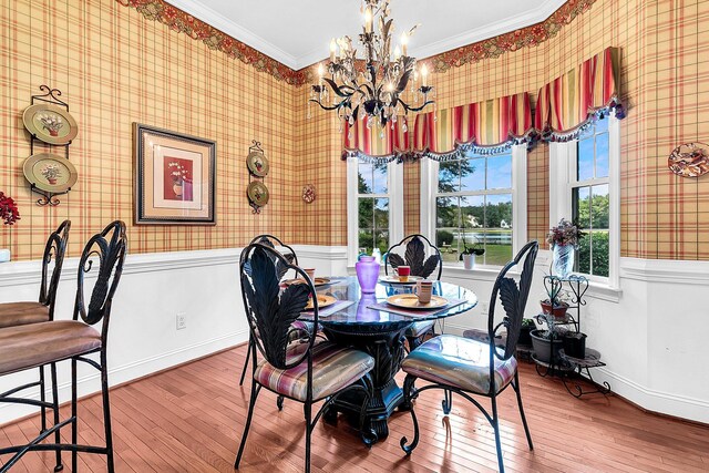 dining area featuring wainscoting, hardwood / wood-style flooring, ornamental molding, and a chandelier