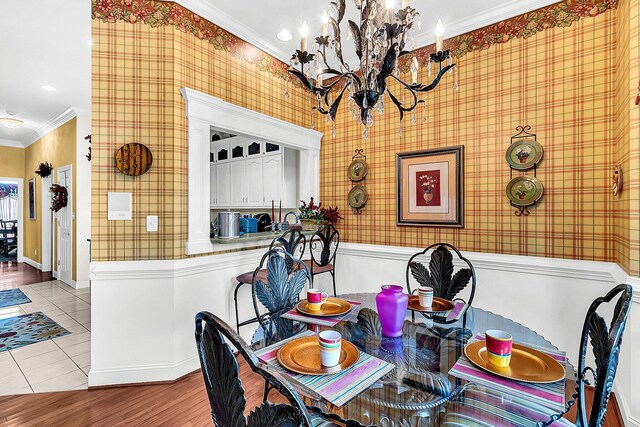 dining space featuring a chandelier, baseboards, ornamental molding, wallpapered walls, and light tile patterned floors