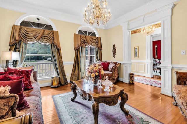 living room with an inviting chandelier, crown molding, hardwood / wood-style floors, and ornate columns