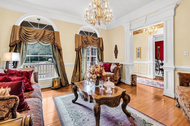 living area featuring decorative columns, crown molding, and an inviting chandelier