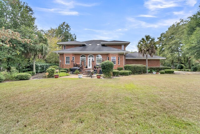 view of front facade with brick siding, french doors, and a front yard