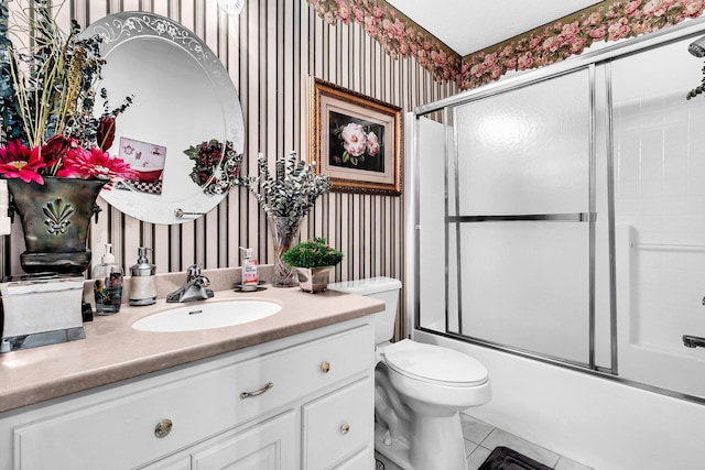 full bathroom featuring tile patterned floors, bath / shower combo with glass door, vanity, and toilet