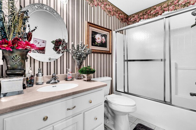 bathroom featuring wallpapered walls, vanity, shower / bath combination with glass door, and toilet