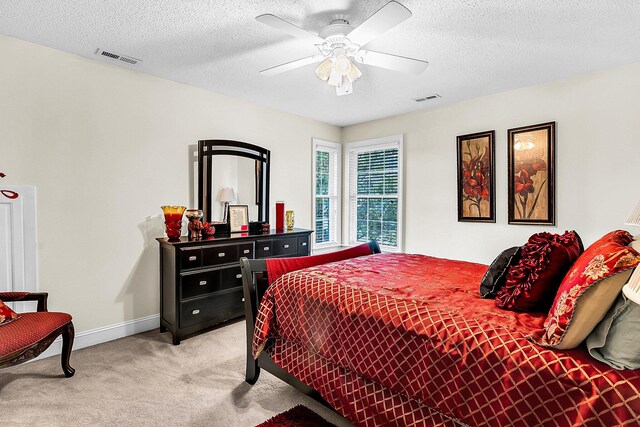 bedroom with light colored carpet, baseboards, a textured ceiling, ceiling fan, and visible vents