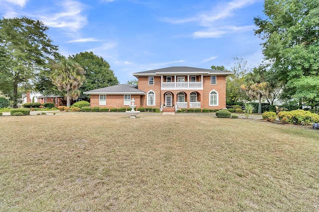 view of front facade featuring a balcony, a front yard, and a porch