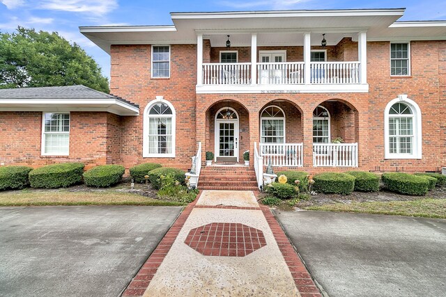 view of front of property featuring a balcony, a porch, and brick siding