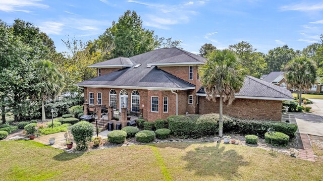 rear view of property featuring a lawn and brick siding