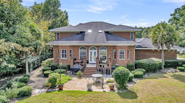 view of front of house with a patio, brick siding, a front lawn, and french doors