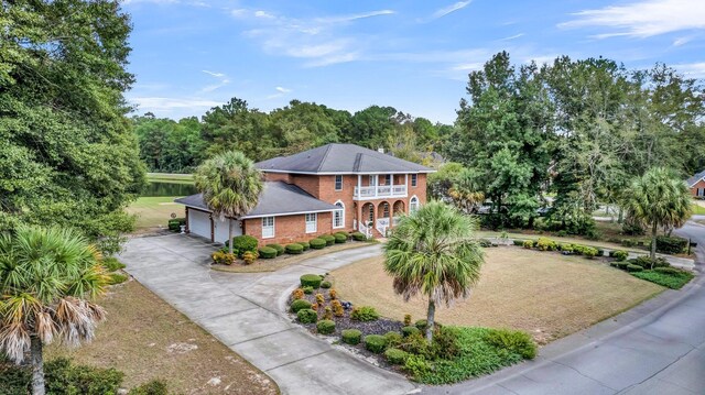 view of front of house with a balcony, an attached garage, brick siding, driveway, and covered porch