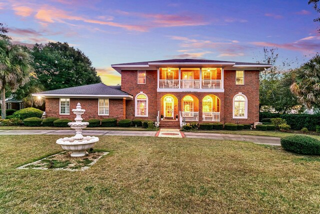 view of front of house with a balcony, a yard, and covered porch