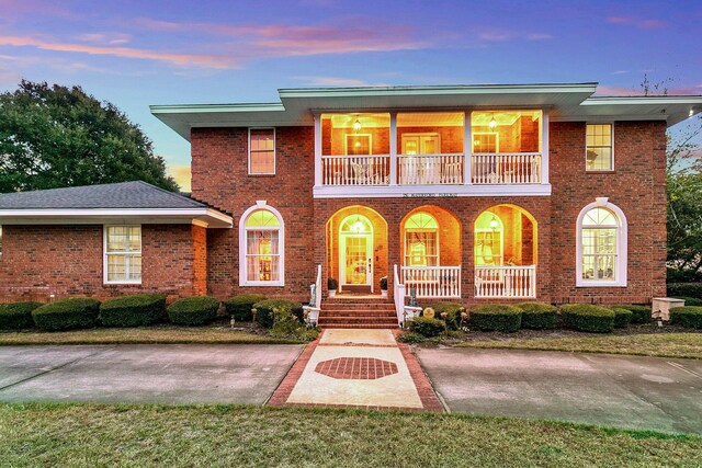 view of front of property with a lawn, a balcony, and covered porch