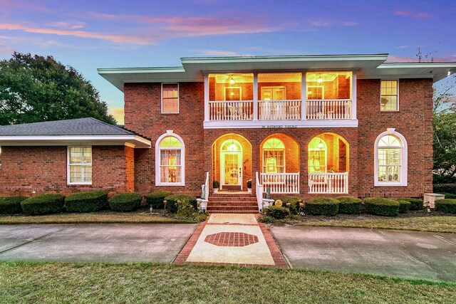 view of front of home featuring a balcony, a porch, and brick siding