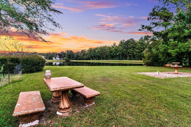 yard at dusk featuring a water view