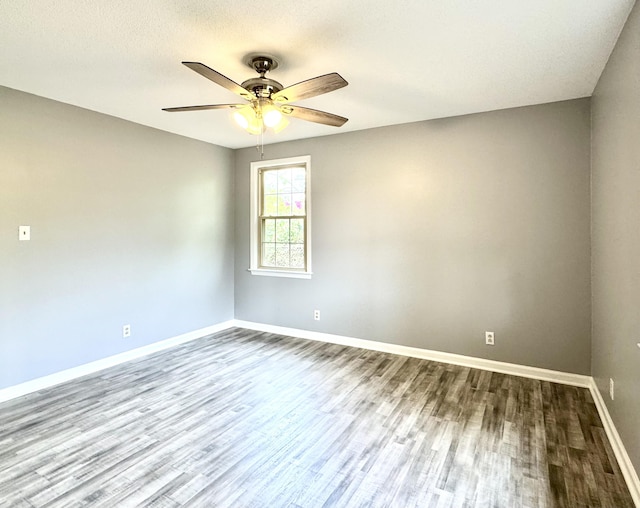 spare room featuring dark wood-style floors, baseboards, and a ceiling fan