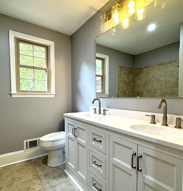 bathroom featuring toilet, double vanity, tile patterned flooring, and baseboards