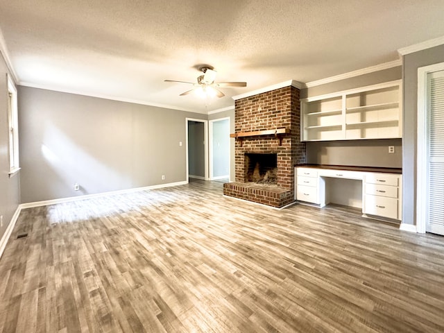 unfurnished living room with ceiling fan, wood finished floors, baseboards, a textured ceiling, and a brick fireplace