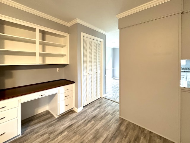 unfurnished office featuring built in desk, ornamental molding, dark wood-style flooring, and baseboards