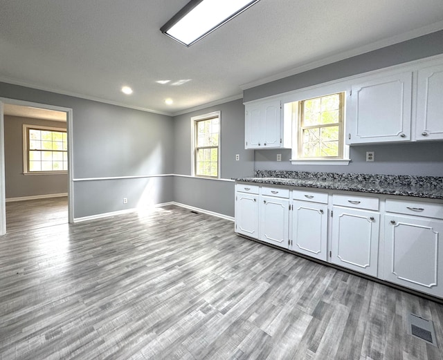 kitchen featuring crown molding, light wood-style floors, white cabinets, and baseboards