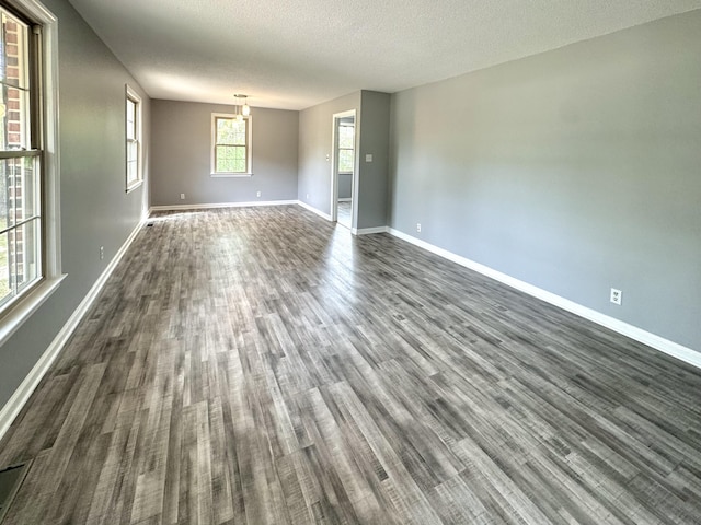 spare room with dark wood-style flooring, baseboards, and a textured ceiling