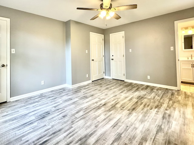 empty room featuring a ceiling fan, light wood-style flooring, baseboards, and a sink