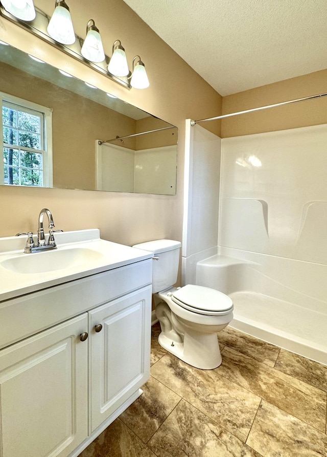 bathroom with vanity, a shower, a textured ceiling, and toilet