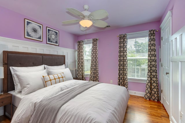 bedroom featuring light wood-style flooring, multiple windows, baseboards, and ceiling fan