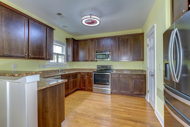 kitchen with stone counters, stainless steel appliances, visible vents, light wood-style floors, and dark brown cabinets