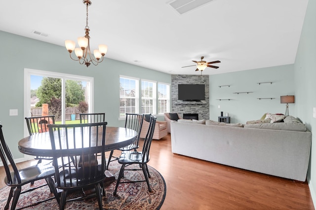 9785 Black Willow Ln, Ladson, SC 29456 - dining room featuring light wood-type flooring, a fireplace, ceiling fan, and a chandelier