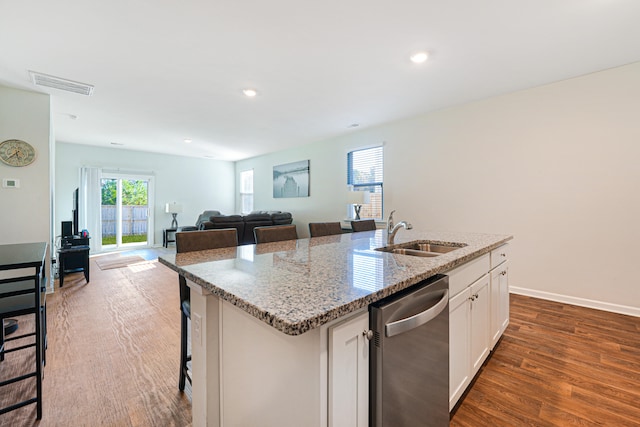 kitchen featuring a kitchen breakfast bar, stainless steel dishwasher, sink, a center island with sink, and white cabinets