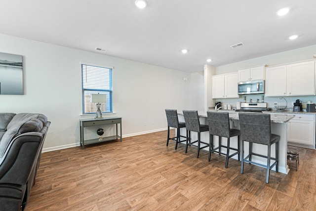 kitchen with a breakfast bar area, light hardwood / wood-style flooring, and white cabinets