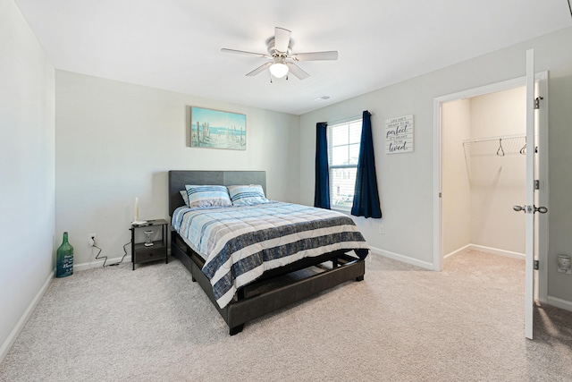 bedroom featuring carpet flooring, a walk in closet, ceiling fan, and a closet